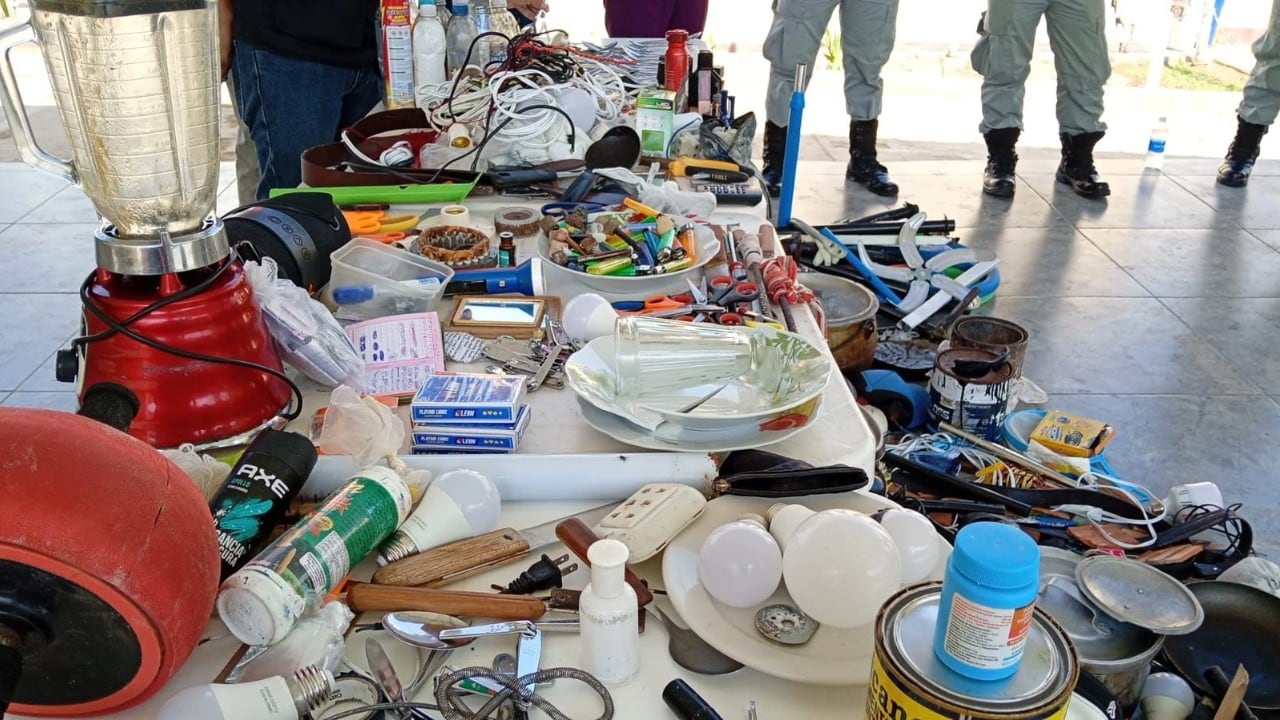 Agentes del INPE exhiben una gran variedad de objetos prohibidos y libretas con anotaciones incautados durante un operativo de seguridad en el Establecimiento Penitenciario Chiclayo. (Foto: INPE)