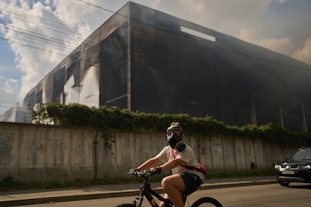 Un residente pasa en bici, con el rostro cubierto con una máscara de gas, por delante de un almacén parcialmente destruido por un ataque con drones rusos, en Brovary, a las afueras de Kiev, el 4 de septiembre de 2026. (AP Foto/Francisco Seco)