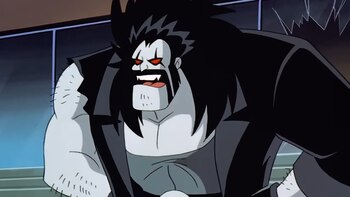 Lobo, el personaje de DC Comics, mira hacia adelante con una expresión feroz, mostrando sus colmillos. Tiene piel gris, pelo negro largo y puntiagudo, barba, y ojos rojos