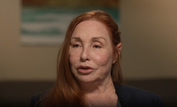 Primer plano de Debra Tate, una mujer con el cabello pelirrojo largo, mirando de frente con un fondo interior desenfocado