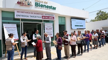 Fila de personas adultas mayores y personal de apoyo frente a un Banco del Bienestar con un letrero indicando 'Último día entrega tarjetas: 25 de abril'.