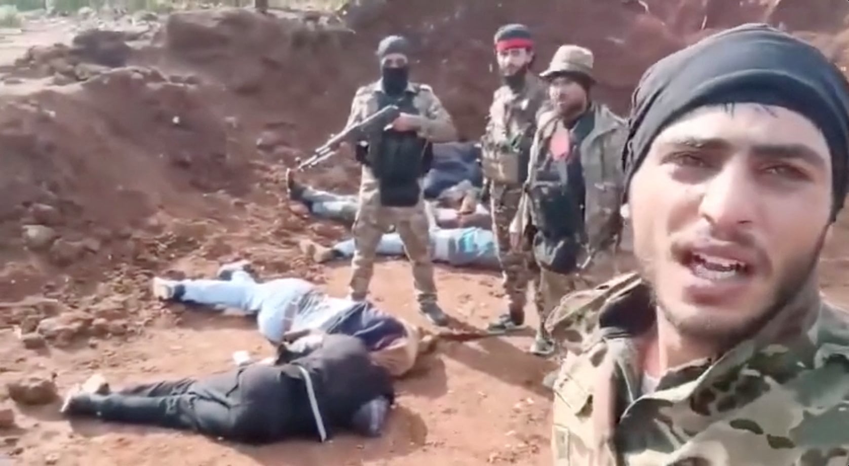 Combatientes junto a cuerpos de alauitas en Sonobar, Siria, en esta captura de pantalla de un video publicado en las redes sociales. (Reuters)