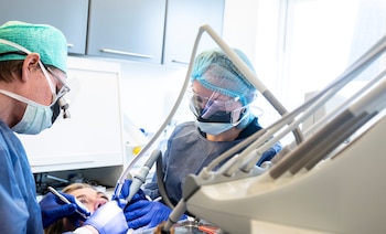 Los dentistas llevan varias capas de equipo de protección personal, incluidas las máscaras N95 y los escudos faciales. (Ritzau Scanpix/Claus Fisker via REUTERS)