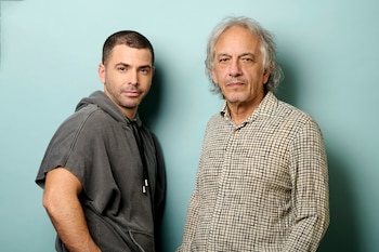 Richard Gadd, con sudadera gris, y un hombre mayor de pelo canoso y camisa a cuadros posan frente a una pared verde azulado claro