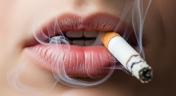 Primerísimo plano de una boca adulta con labios entreabiertos exhalando humo de cigarrillo, con la brasa encendida y la piel con textura realista.
