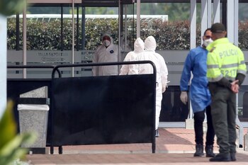 Expertos con vestimentas protectoras entran en un centro deportivo donde están aisladas personas colombianas que vivían en Wuhan y regresaron al país (REUTERS/Luisa Gonzalez)