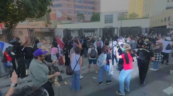 Multitud de personas vista desde arriba en una calle, muchos con cámaras y teléfonos. Barreras de metal separan a la gente de un edificio grande y árboles