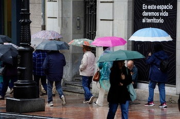 Turistas protegiéndose de la lluvia en el centro de Oviedo. (Paco Paredes/EFE)