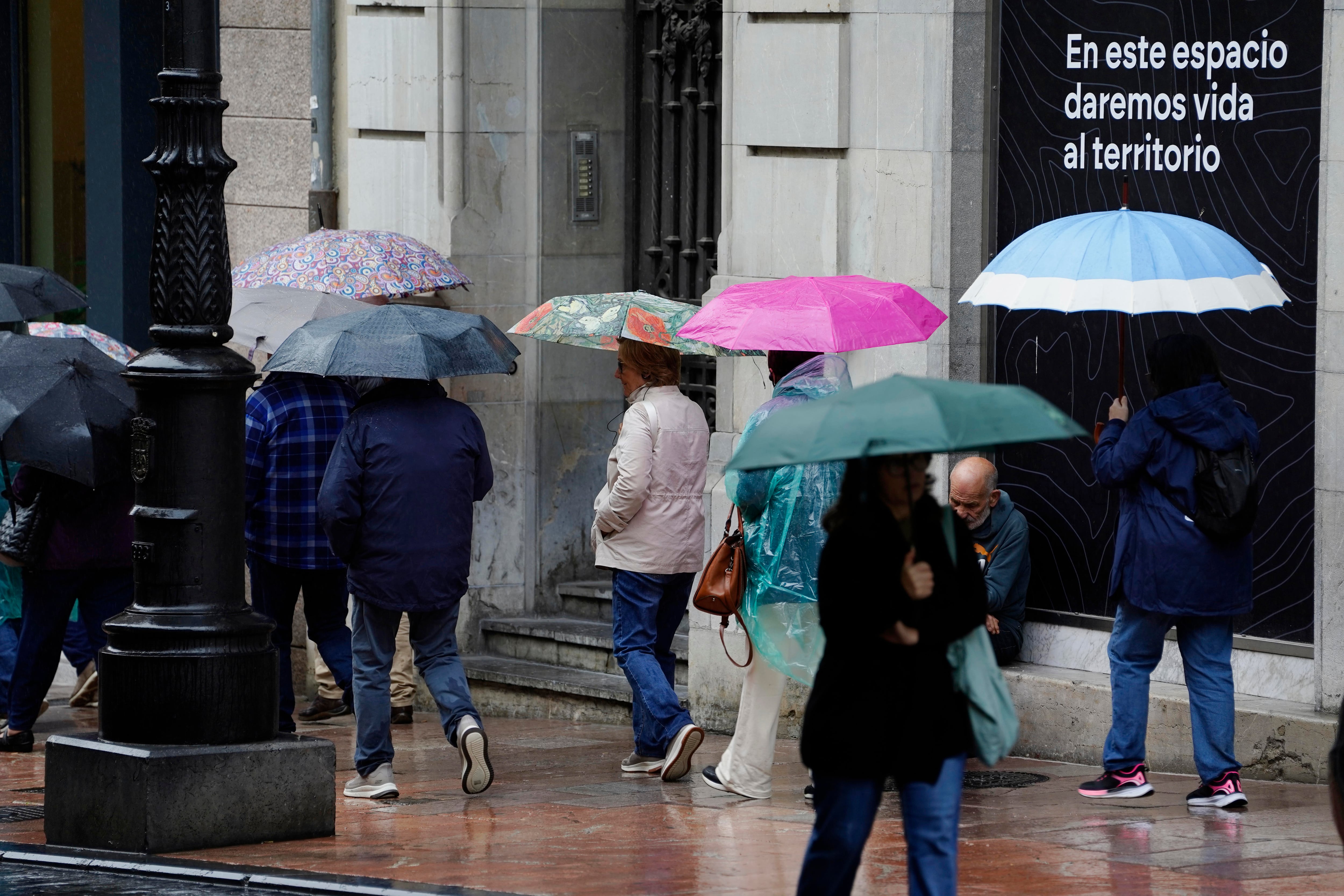 Turistas protegiéndose de la lluvia en el centro de Oviedo. (Paco Paredes/EFE)