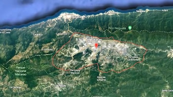 Mapa satelital de una zona montañosa y costera con una línea roja que delimita la ciudad de Caracas y un marcador rojo