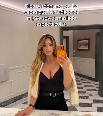 Mujer de cabello largo y ondulado, con top negro, falda y chaqueta clara, toma una selfie con un teléfono naranja. Un texto se superpone a la imagen