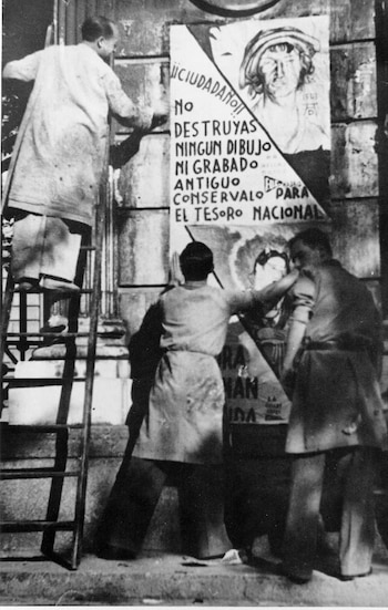 Alumnos de la Escuela de Bellas Artes fijando los carteles en defensa del tesoro artístico durante la Guerra Civil. (Fondo de la Junta del Tesoro Artístico/ Instituto del Patrimonio Cultural de España, Ministerio de Cultura)