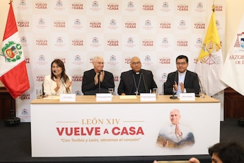Cuatro personas sentadas en una mesa frente a micrófonos, con banderas de Perú y el Vaticano y un panel con el lema León XIV vuelve a casa