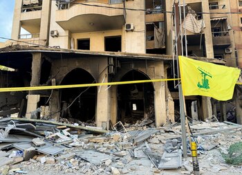 Una bandera de Hezbollah ondea frente a un edificio dañado, tras los ataques israelíes contra los suburbios del sur de Beirut. (REUTERS/Ahmad Al-Kerdi)