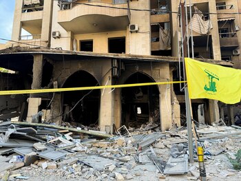 Una bandera de Hezbollah ondea frente a un edificio dañado, tras los ataques israelíes contra los suburbios del sur de Beirut. (REUTERS/Ahmad Al-Kerdi)