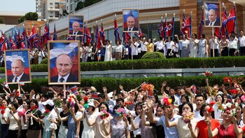 Norcoreanos sostienen retratos de Putin,