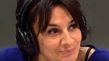 Primer plano de una mujer con cabello oscuro y auriculares negros que viste una prenda azul