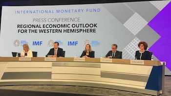 Cinco panelistas sentados en una mesa de conferencia. Detrás, una pantalla grande muestra "Fondo Monetario Internacional" y "Conferencia de Prensa"