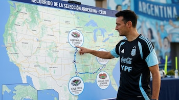 Lionel Scaloni con una camiseta de la selección argentina apuntando a un mapa de Estados Unidos que muestra el recorrido y estadios del equipo.