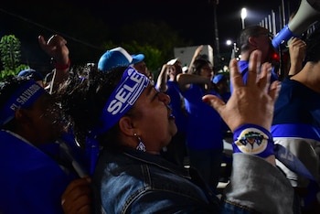 Personas portan cintas azules en la cabeza con el texto SELE y distintivos de El Salvador mientras alzan los brazos en la noche