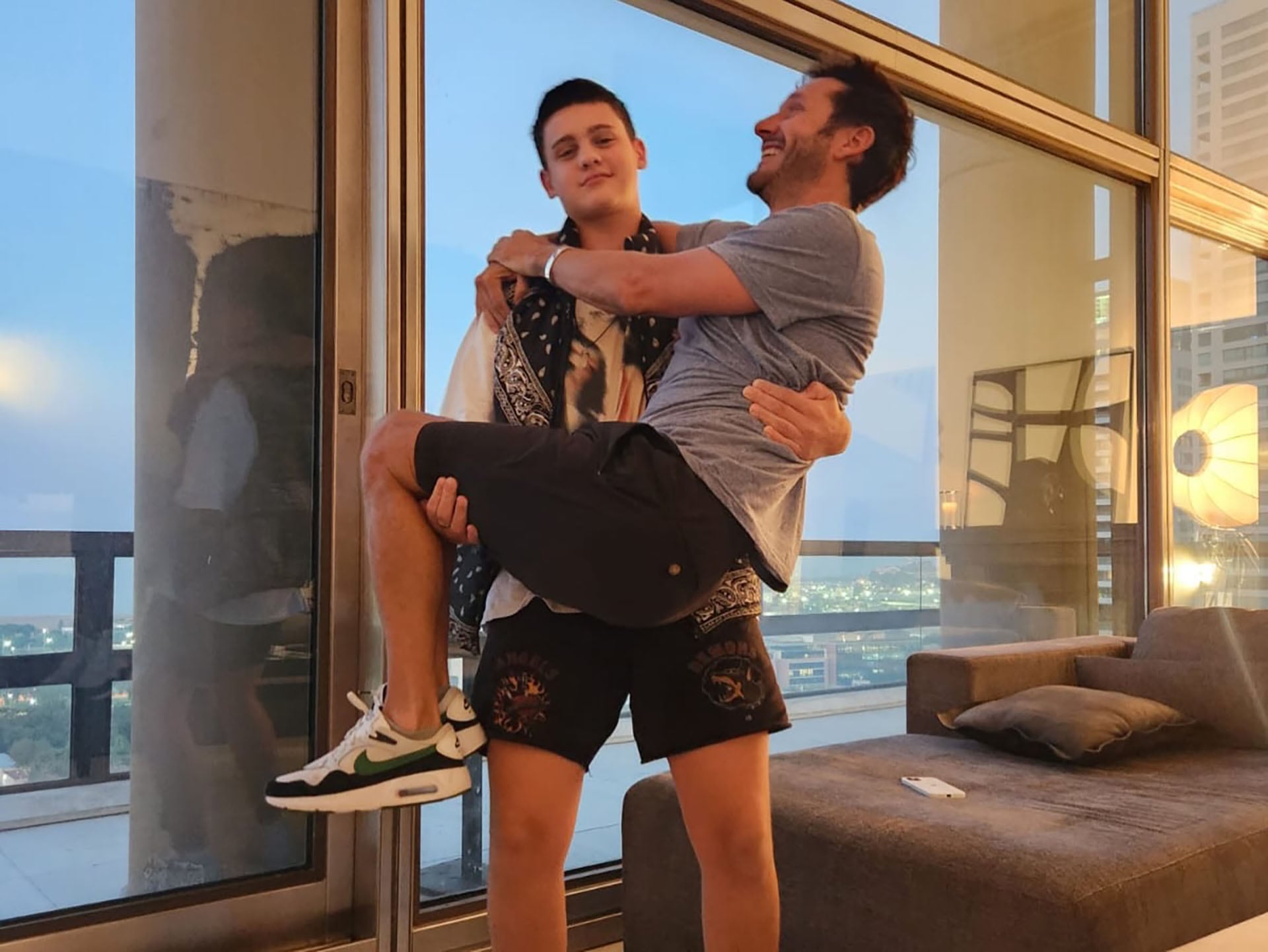 El joven levantando a su padre en brazos, dejando en claro su fuerza