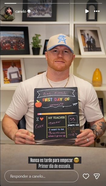 Canelo Álvarez, un hombre con cabello rojizo y barba, sonríe a la cámara sosteniendo un cartel de "Primer Día de Universidad". Viste una gorra y camiseta clara