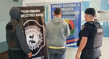 Dos policías con chalecos tácticos custodian a un hombre vestido con sudadera gris frente a paneles de la Policía de Misiones