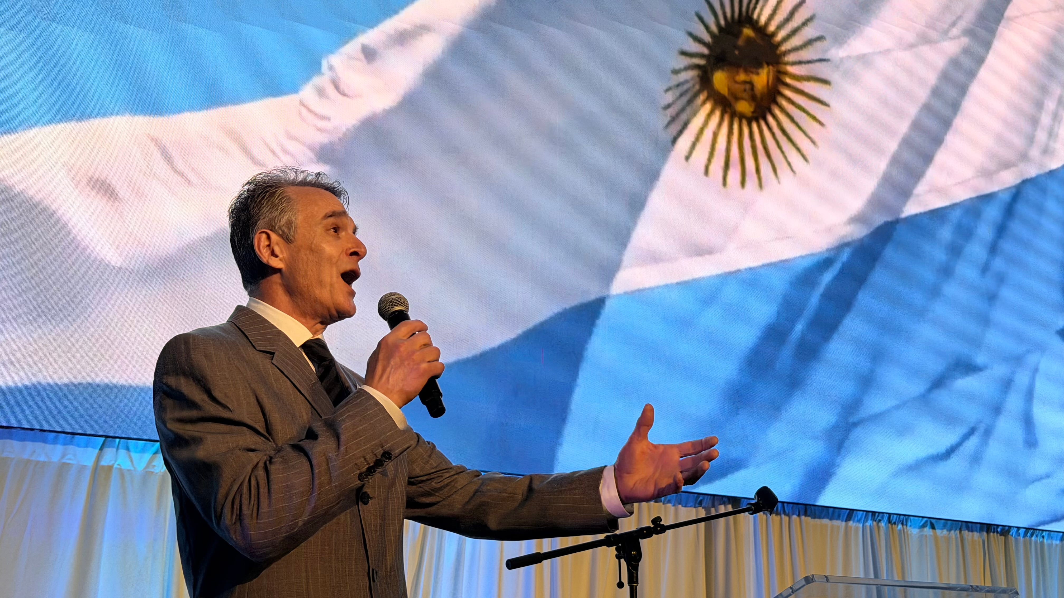 El reconocido cantante Daniel Bouchet interpreta con emoción el himno nacional argentino durante una gala solemne.
