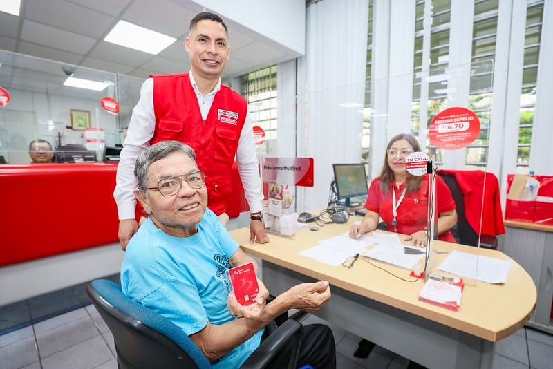 Un beneficiario del programa Pensión 65, Segundo Rojas Reyes (81), recibe su tarjeta de débito del Banco de la Nación, junto a personal del banco, marcando el inicio de su subvención (MIDIS)