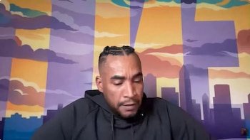 Don Omar viste una sudadera negra ante un fondo ilustrado con siluetas de edificios y nubes en tonos naranjas y morados