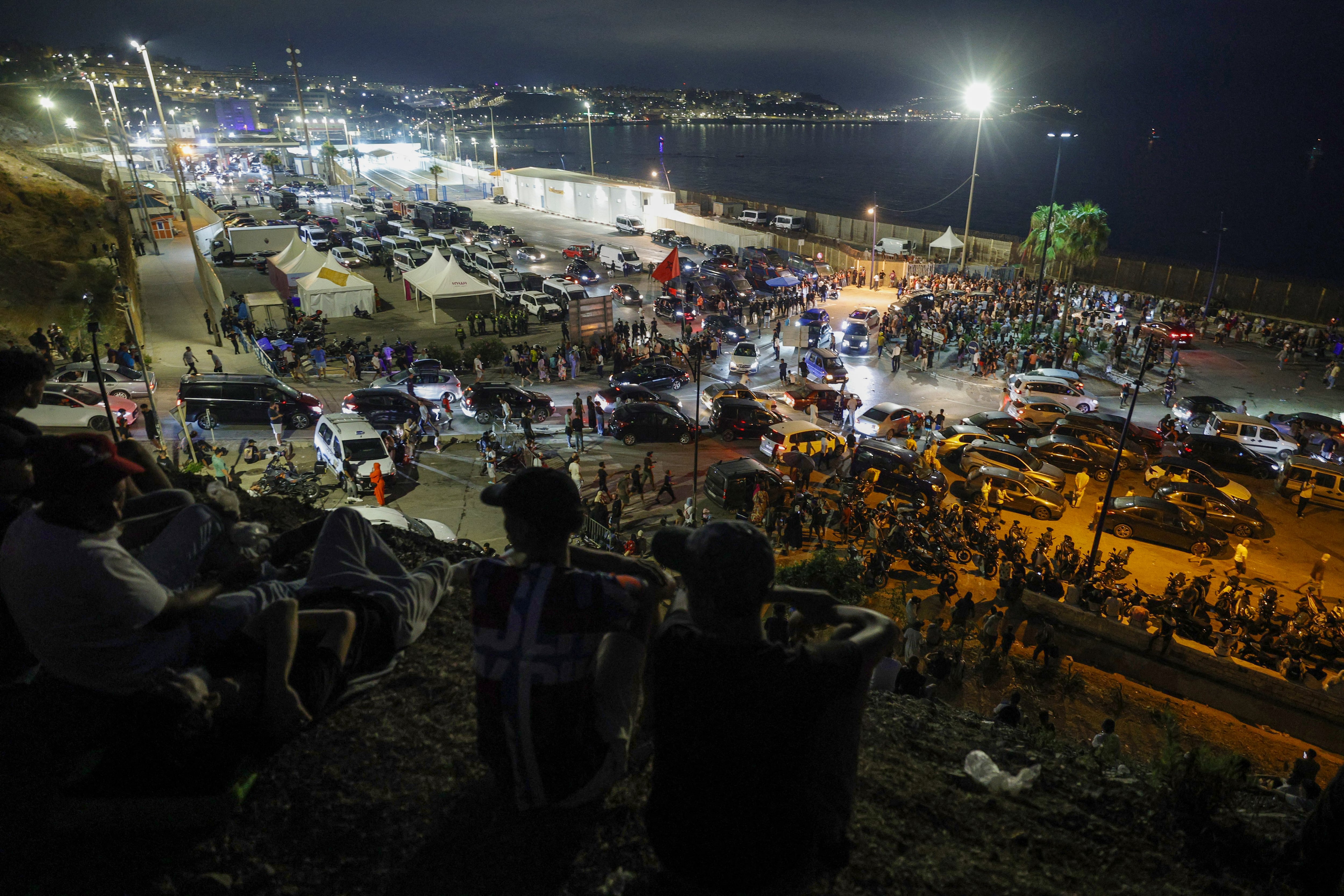 Una multitud de personas y vehículos se concentra en la frontera de Ceuta por la noche, en un punto de acceso hacia España (AFP).