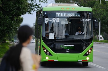 Primer plano de un autobús eléctrico verde de Mi Transporte con el letrero "TTE NORTE" visible, circulando por una calle con árboles frondosos