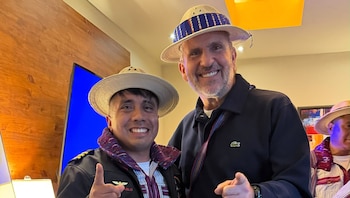 Dos hombres sonrientes con sombreros y prendas de vestir tradicionales posan apuntando hacia el frente