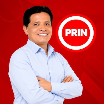 Retrato de Renso Evert Aguilar Velarde con camisa azul clara y brazos cruzados, junto al logotipo del partido PRIN sobre fondo rojo