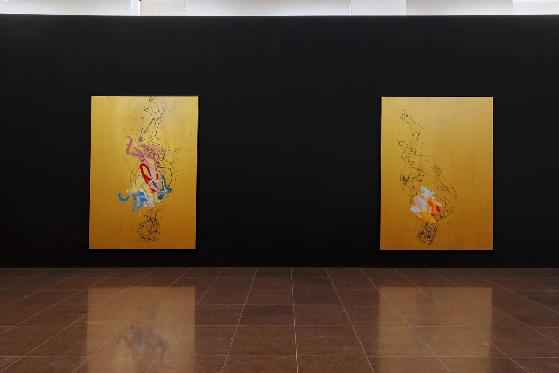 Dos cuadros del renombrado artista Georg Baselitz, caracterizados por figuras invertidas y toques de color sobre fondos dorados, se exhiben en una pared negra en una galería de arte. (Celestia Studio)