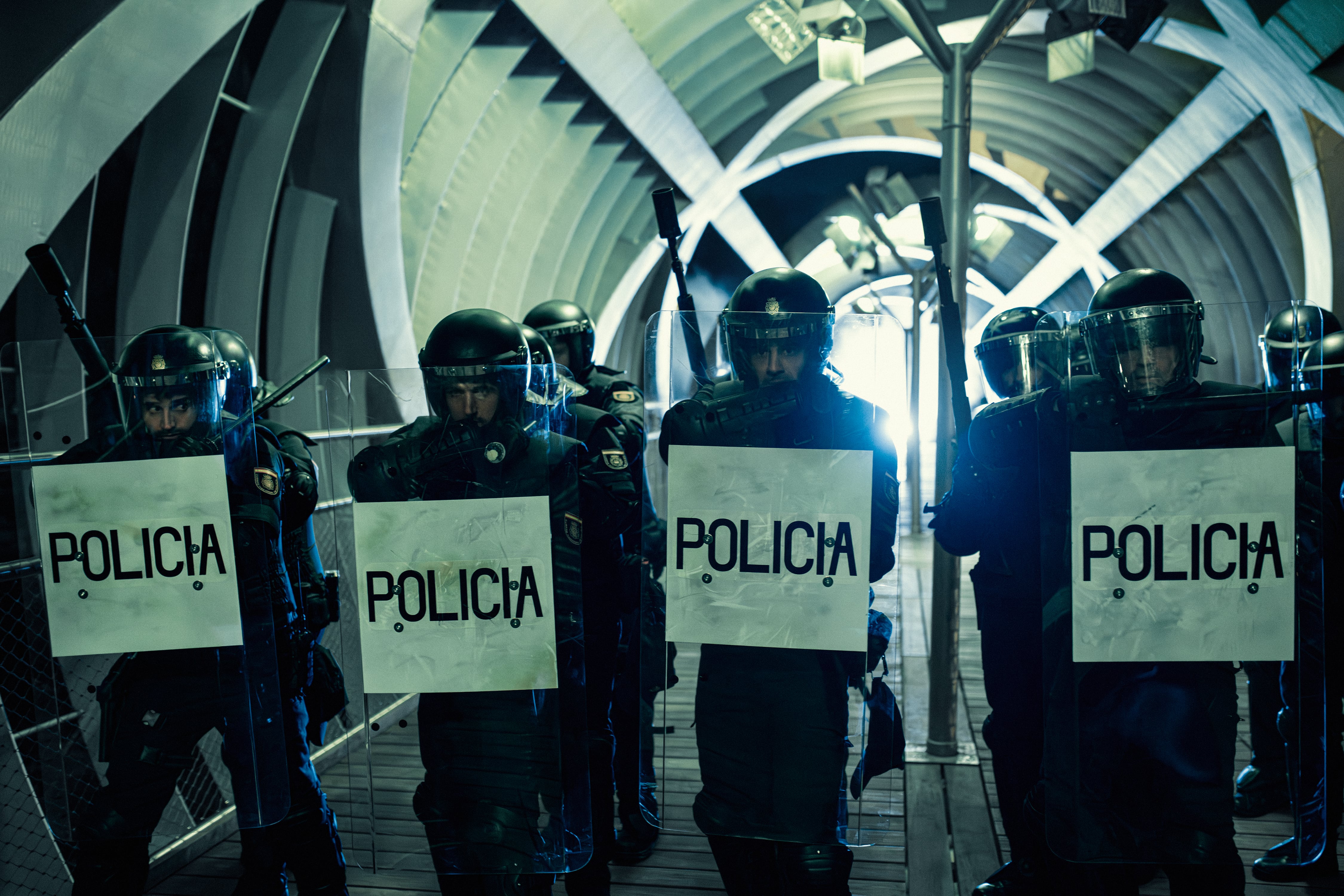 Agentes de policía antidisturbios, equipados con cascos, visores y escudos con la palabra