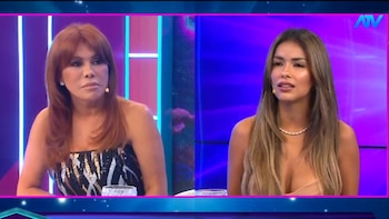 Dos mujeres sentadas en un set de televisión con luces azules y moradas de fondo. Una mujer tiene cabello rojizo, la otra tiene cabello castaño claro