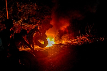 Residentes del Parque Nacional Morrocoy prenden fuego a escombros mientras bloquean una carretera durante una protesta por los cortes de electricidad cerca de Tucacas, en el estado Falcón (Venezuela), el 5 de octubre de 2026 (Maryorin Mendez /AFP)