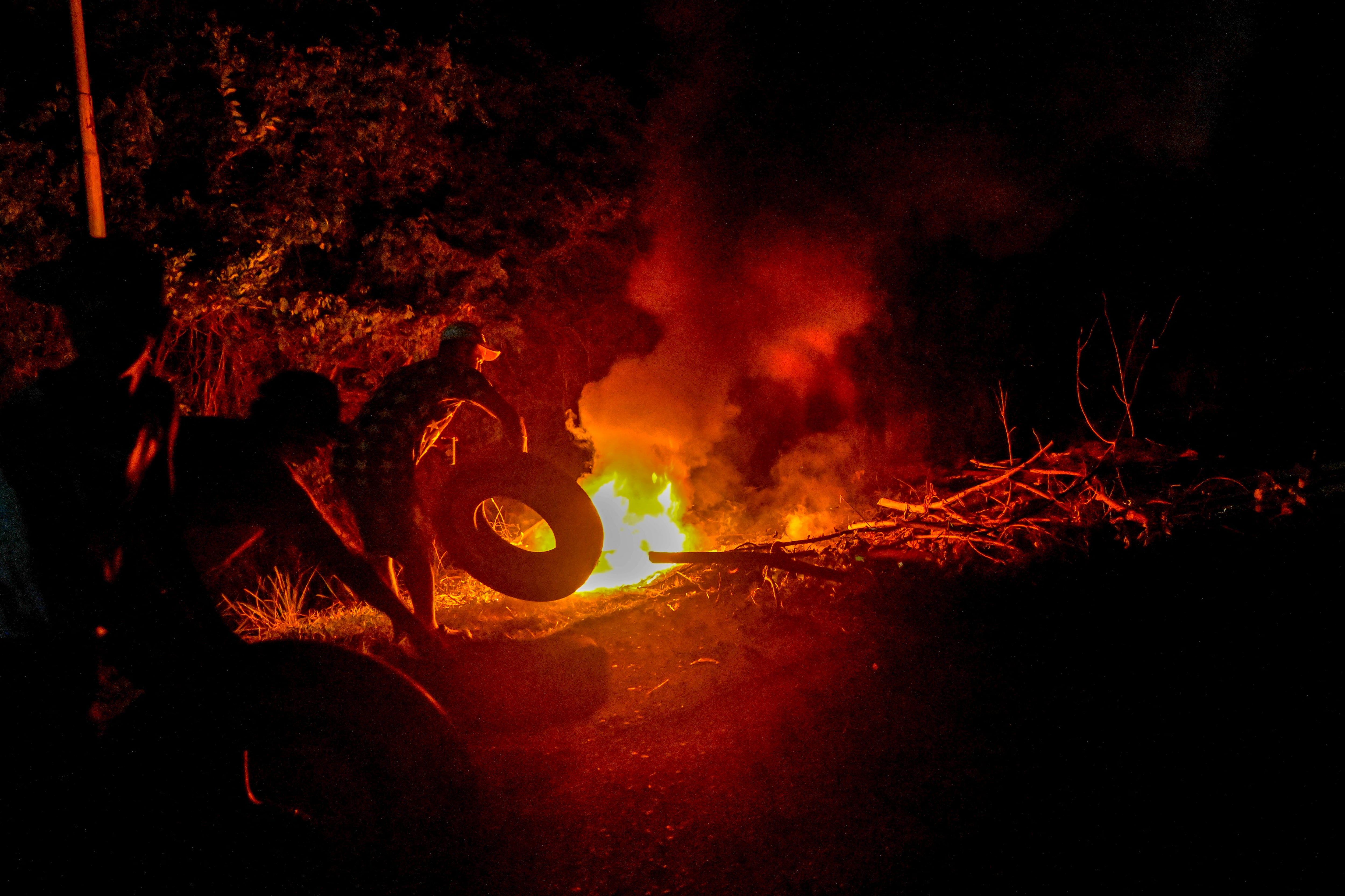 Residentes del Parque Nacional Morrocoy prenden fuego a escombros mientras bloquean una carretera durante una protesta por los cortes de electricidad cerca de Tucacas, en el estado Falcón (Venezuela), el 5 de octubre de 2026 (Maryorin Mendez /AFP)