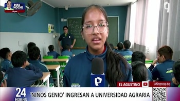 Una joven con gafas y uniforme azul habla a un micrófono. Detrás, otros alumnos sentados, un profesor de pie y un pizarrón con fórmulas