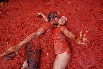 Una pareja se besa sobre un charco de tomates durante la "Tomatina" en el pueblo de Buñol, cerca de Valencia, España, el miércoles 27 de agosto de 2025. (AP Foto/Alberto Saiz)