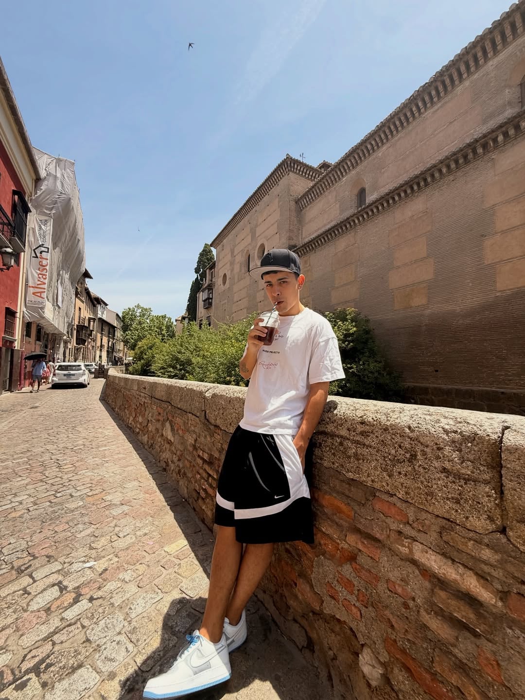 Trueno disfruta de un refresco mientras posa casualmente en una calle empedrada durante sus vacaciones