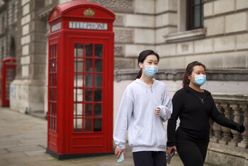 Mujeres con mascarillas caminan en