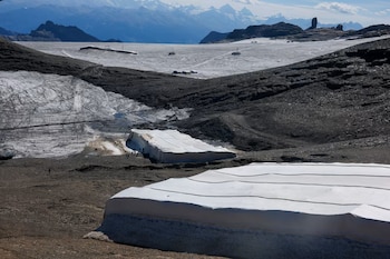 Un paisaje de montaña con grandes mantas blancas colocadas sobre bloques de nieve en un terreno rocoso