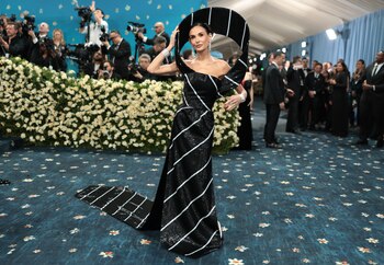Demi Moore y un look que tuvo protagonismo en la gala. un vestido de gala negro con lentejuelas y líneas diagonales en blanco plateado que recorren toda la prenda. La silueta es ajustada al cuerpo hasta la cadera y luego desciende con una pequeña cola que se extiende hacia atrás, siguiendo el mismo patrón de franjas. El diseño incorpora un elemento escultórico llamativo
