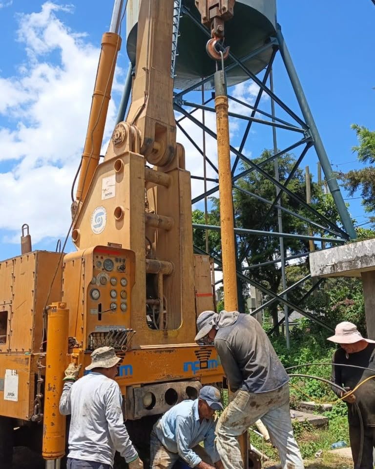 Un grupo de operarios maneja una plataforma de perforación para la construcción de un pozo de agua junto a un tanque elevado. (Infom Guatemala)