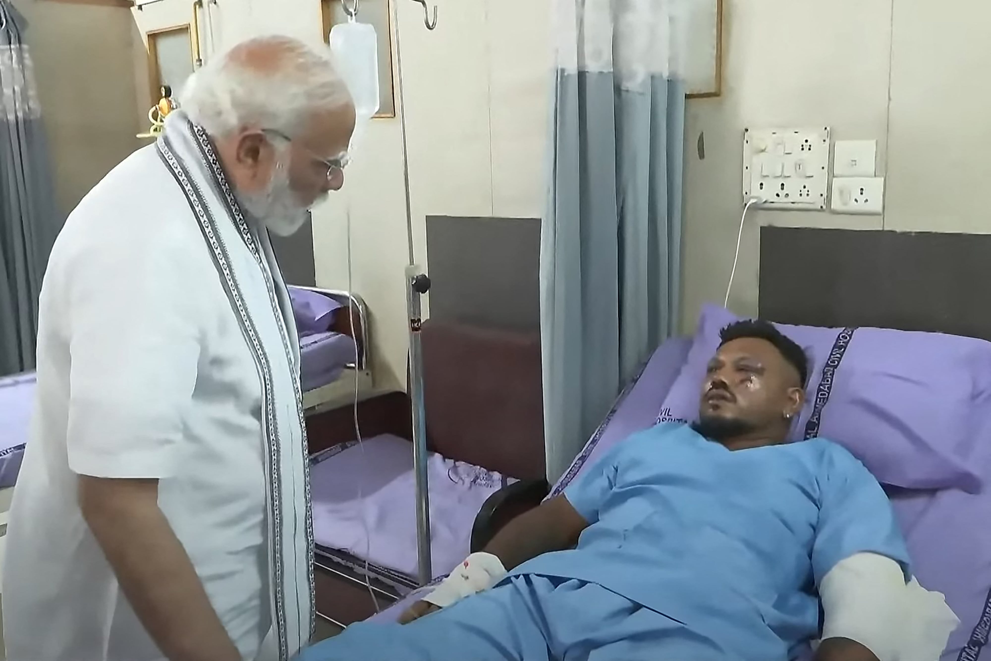 Esta captura de pantalla muestra al primer ministro de la India, Narendra Modi (izquierda), reuniéndose con Vishwash Kumar Ramesh, único superviviente del accidente del vuelo 171 de Air India, en un hospital de Ahmedabad (AFP)