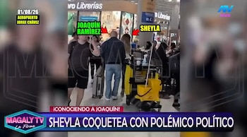 Sheyla Rojas y Joaquín Ramírez de espaldas caminando en el aeropuerto. Hay un carro de limpieza amarillo, personas, y rótulos de librerías