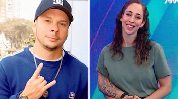 Hombre con gorra negra y sudadera azul posa haciendo un gesto con la mano. Mujer con camiseta verde y tatuaje en el brazo posa sonriendo.