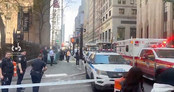 Vista de calle con una ambulancia, un coche de policía de NYPD y varios oficiales en el centro de Nueva York, detrás de una cinta de precaución